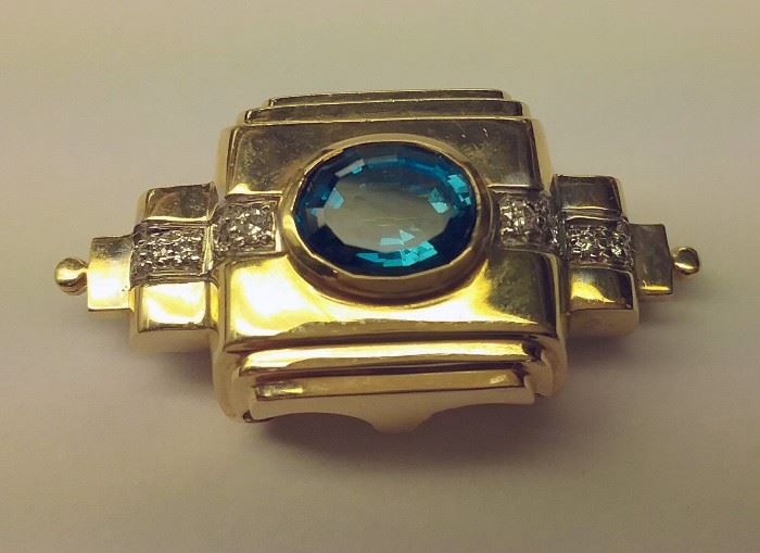 Deco inspired gold pin with 10 diamonds and central blue stone. 1.25" wide
