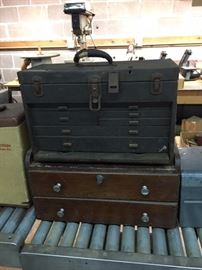 Old tool box sitting on a vintage wood cabinet with lock and key.