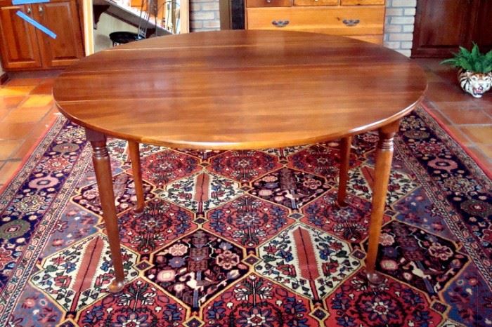 Solid cherry drop leaf table with two leaves and pads.