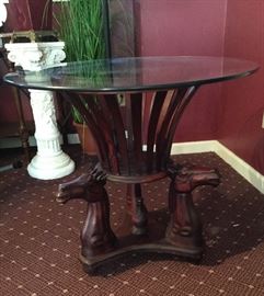 Unique glass top table with carved horse heads base.