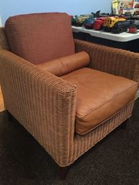 Unique wicker chair with leather and cloth cushions.
