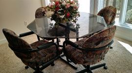 Black Metal Dinette set with Octagonal Smoked Glass Top and 4 upholstered chair on castors.