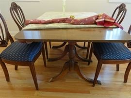 Dark wood dining room table, the side ends fold down. One 10" leaf is included. Size of table is 5' 6" long x 3'4" wide x 2'6" tall. One of the brass "feet" end is missing.