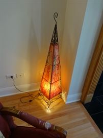 Turkish handmade dyed goat skin floor lamp, in reds and golds & black; areas of the skin are split (torn) from the heat of the lamp. Unavoidable. Still beautiful.