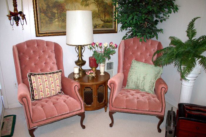 Upholstered wingback armchairs, side table, brass lamp, silk plants
