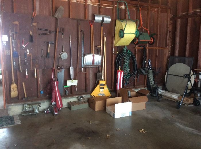 The garage is full of yard tools and hand tools. 
