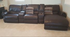 Theater style reclining brown leather sofa! Electric buttons recline the seats back and at your feet features cup holders, outlets, storage and USB ports