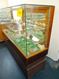 Lot 114: Large Group of US Rough Gems and Minerals in Display Case
Glass diplay case with separate base measures 69" L x 20" D x 51" H. One front edge is chipped on top left front corner. 2 glass insert shelves. Sliding rear doors. This grouping is comprised of many wonderful United States samples collected in the 50's and 60's from the collection of Claude Davis. Approximately 69 rough gems and minerals. See photographs for complete listings. 