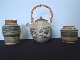 Lot 271: Three 1970's Studio Pottery Pieces by Michael Pitts
Three signed vintage studio pottery stoneware vessels by Watkinsville, GA potter Michael Pitts dated from the 1970's. The bamboo handles teapot with bauhaus "Picassoesque" design is 7" tall without handle. It features a grey wash over the navy blue design. The other two are corked crocks. The taller geometric scored piece measures 5.5" high. The striped banded crock measures 3.5" high. No cracks, chips or kiln flaws noted. On the teapot there is a white milky area of glaze under the spout. It's signed Pitts '75. From living estate of Charles Rathbun.