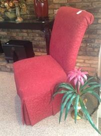 Single red parson chair; artificial plant in vase