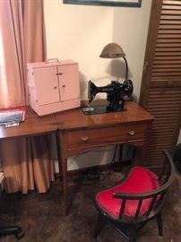 Vintage Singer sewing machine 99K.  Beautiful condition, in its sewing table.  To its left is a darling home made thread keeper.  Small chair with crescent moon shape.