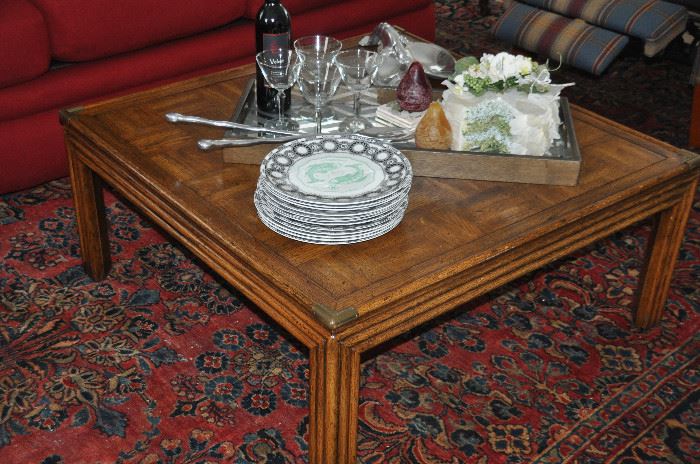 Wonderful 37” square wooden coffee table with antique brass detail.  16” h. Shown with great entertaining serving pieces including a complete "Sign of the Zodiac" plate set by Royal Doulton