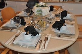 Beautiful table setting complete with white porcelain tablescape, stainless flatware and footed goblets. 