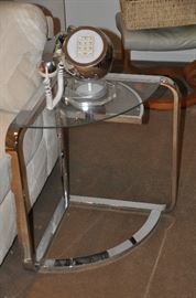 Contemporary polished chrome and glass side table with swinging lower shelf, 29"w x 22"h x 18"d. Also shown is a fantastic vintage chrome and lucite phone by Teleconcepts. 