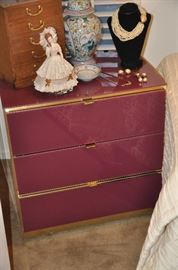 Cranberry colored lacquer 3 drawer nightstand/side table, 24.5"w x 25"h x 17"d. Shown with a vintage ginger jar, porcelain figurine, a 5 drawer wooden musical jewelry box made in Japan and more jewelry!