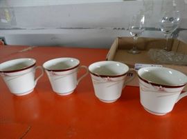 Lot of coffe cups, wine glasss and a candy plate.