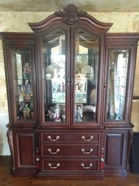 Pristine Bernhardt "La Scala" collection lighted mahogany china cabinet, with beveled glass and mirrored back, measuring 94" high at tallest point x 77" wide x 22" deep.
The china cabinet has beveled glass doors, is lighted and has 3 glass shelves. Base has 3 drawers and 2 doors with 1 shelf inside each; originally cost $4,850.00 in 2001.