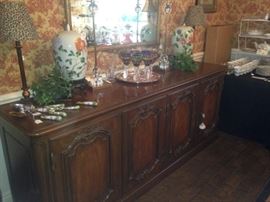 Extra long buffet provides serving and storage space; a gold framed mirror is above the buffet.
