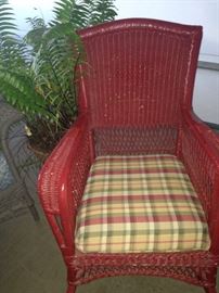 Red wicker rocker with upholstered cushion; live fern
