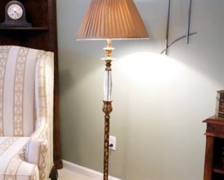 Artist made metal wall clock and a glass and metal floor lamp along side Chippendale style wing armchair