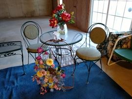 Metal glass top bistro table with two chairs and a bird cage wall art with faux flowers