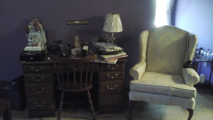 wing back chair and knee hole desk, chair and office supplies.