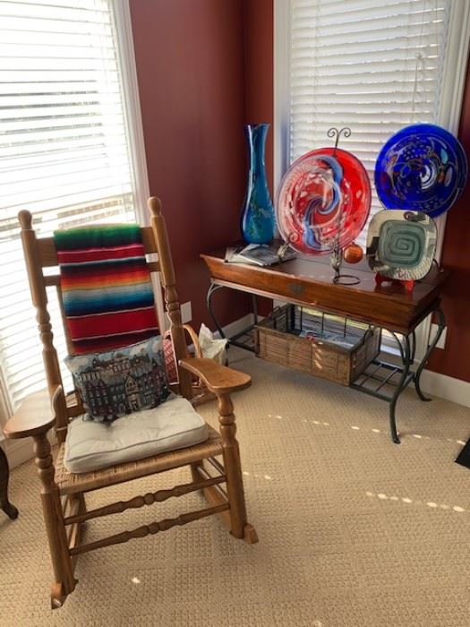 Artglass, vintage rocking chair, handwoven blanket, wooden hutch, ornate storage boxes.
