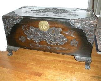Landing-Second Floor:  An antique Asian-style trunk is heavily carved on all sides and has a large brass escutcheon.  The trunk measures 39-l/2" wide x 21-l/2" deep  x 21-l/2" tall.