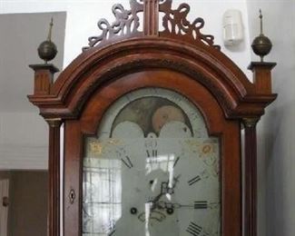 Foyer:  Three brass finials and fretwork adorn the top of the bonnet, and a moon phase and hemispheres decorate the clock face.  (Note:  the second hand is missing.)