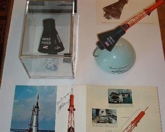 Collectibles-in Kitchen:    In 1962, the NASA Mercury Spacecraft was manned by John Glenn, a former NASA pioneer, and the first American to orbit the Earth (he did three orbits).  These are four separately priced items that are a tribute to Mercury's trip in space:  A Mercury capsule model and astronaut is in the plastic cube (its box is behind it); the Mercury shuttle; a photo of the Mercury shuttle; and a brochure autographed by astronaut John Glenn.