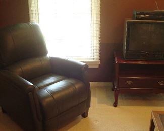 Bedroom #1-Upstairs:  A deep grey recliner is like-new!  To the right is a cherry TV stand with open shelf and one drawer.  The TV and VHS machine are priced separately