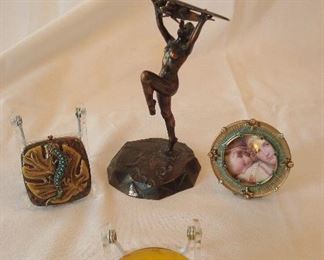 Collectibles-in Kitchen:  Two signed [2002] JAY STRONGWATER items (compact with lizard and a photo frame) flank a bronzed Art Deco  "Universal Transportation" advertisement of a nude woman holding up an airplane.  On the bottom is an amber paperweight with intaglio fish design.