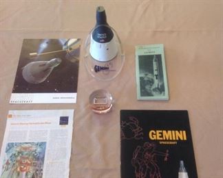 Collectibles-Kitchen:  Various Gemini (NASA-McDonnell) spacecraft documents surround a Gemini space shuttle model and an encased actual piece of the Gemini launch pad.  The lucite disc states:   "Space History Complex 19 Gemini Launch Pad."