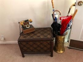 rattan chest, brass umbrella stand with a bevy of umbrellas