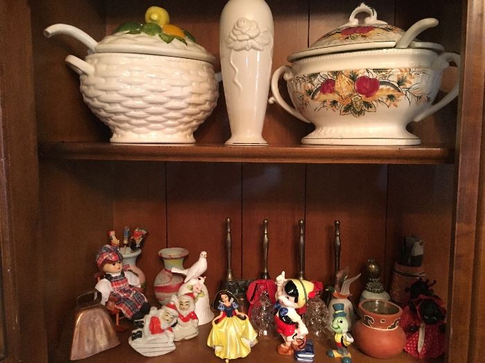 Lower shelf: New Orleans babies and Walt Disney characters, bells. top shelf: Soup tureens