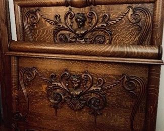 Ornate and rare tiger oak headboard and footboard with high relief carved lady's face, horizontal column trim, claw feet