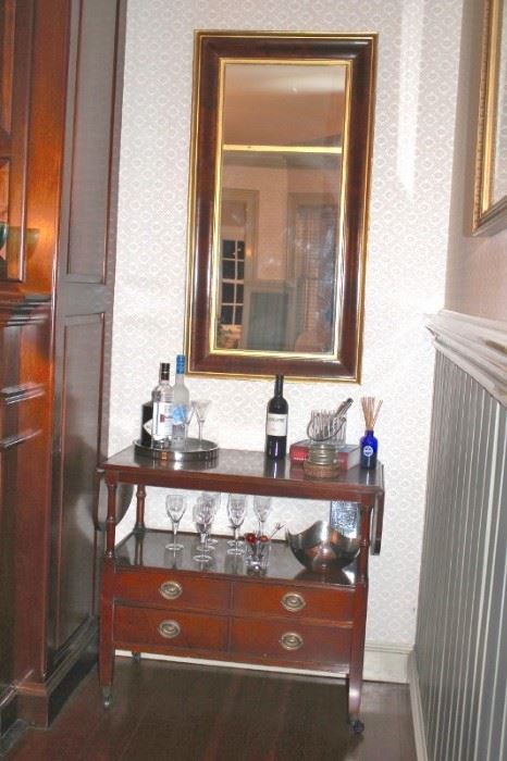 Small Drop-leaf Cabinet with Stemware and Bar Items and Framed Rectangular Mirror