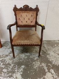 vintage parlor chair with original covering and rollers on front legs