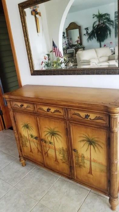 Entry cabinet with 3 drawers and 3 doors with Palm trees scene on front and rattan corner "posts".  Large bronze color rectangular mirror.