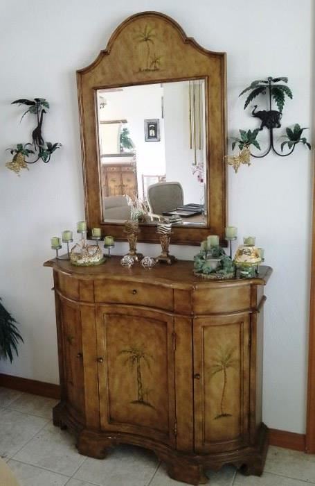 Curved front credenza with Palm Trees on each of 3 doors and inside shelf and one drawer. Matching curve top mirror. Animal print candlesticks. Giraffe and Elephant metal Pam tree sconces. Resin candle holders also in animal theme.