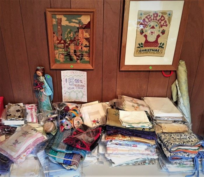 A table filled with personal kitchen linens, tablecloths and sewing items