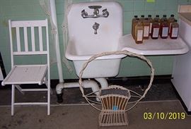 Embalming fluid bottles, porcelain sink w/ attached side tray, funeral basket, white wood folding chair