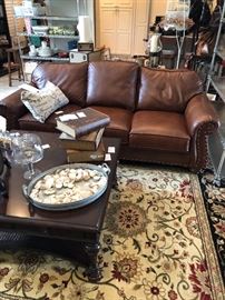 The leather sofa looks great on the area rug and with the oversized mahogany coffee table