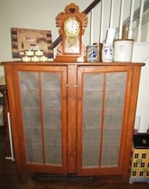 Primitive cupboard, antique mantle clock, 2 newer collectible Manchester crocks, antique crock w/ cover, misc. decor