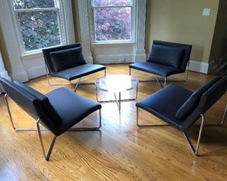 Minotti set of four leather and chrome chairs centered around a Minotti lucite and chrome cocktail table. 