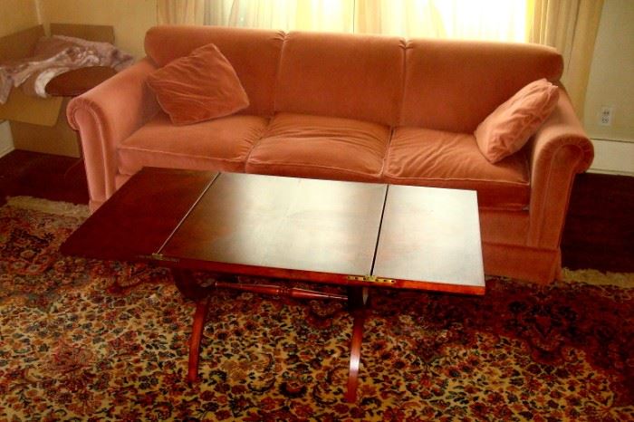 Vintage pink upholstered sofa and regency style folding leaf coffee table.