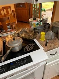 Kitchenalia including pots and pans, Pyrex glass dishes, measuring cups, strainers, vintage crocks, cheese graters and more.