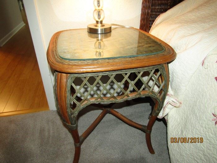 (2) A SET OF END TABLES THAT ARE RATTAN WITH GLASS TOPS FOR COMPANY