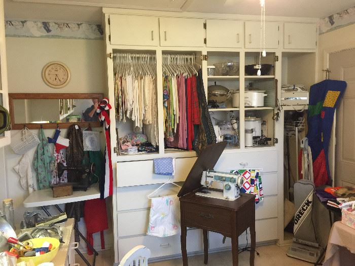 Lots of table cloths, runners, and bridge cloths.  Small kitchen appliances, Mid-Century sewing machine in cabinet, a vintage Singer sewing machine.