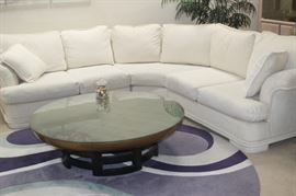 Off white fabric sectional. Asian themed round coffee table with glass top, round area rug.